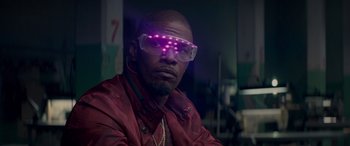 Movie still from “Baby Driver” (2017), directed by Edgar Wright – A man wearing a pair of glasses with purple lights on them; Close Up shot, Low angle