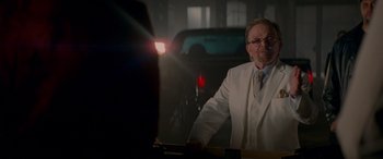 Movie still from “Baby Driver” (2017), directed by Edgar Wright – A man in a white suit standing in front of a car; Medium shot, Over the shoulder angle