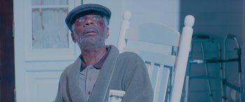 Movie still from “Baby Driver” (2017), directed by Edgar Wright – An old man with a beard and a hat is sitting in a rocking chair; Close Up shot, Low angle