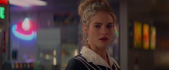 Movie still from “Baby Driver” (2017), directed by Edgar Wright – A young woman with blonde curly hair wearing a black and white shirt; Close Up shot, Over the shoulder angle