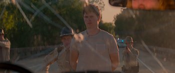 Movie still from “Baby Driver” (2017), directed by Edgar Wright – A man in a police uniform standing next to another man; Medium shot, Over the shoulder angle