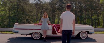 Movie still from “Baby Driver” (2017), directed by Edgar Wright – A woman standing in front of a man standing in front of a car; Wide shot, Low angle