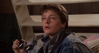 Movie still from “Back to the Future” (1985), directed by Robert Zemeckis – A young man holding a pair of sunglasses; Close Up shot, Over the shoulder angle