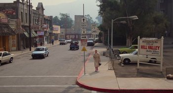 Movie still from “Back to the Future” (1985), directed by Robert Zemeckis – A man walking down the street in a trench coat; Extreme Wide shot, High angle