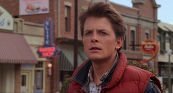 Movie still from “Back to the Future” (1985), directed by Robert Zemeckis – A man in a red jacket is standing in front of a building; Close Up shot, Over the shoulder angle