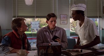 Movie still from “Back to the Future” (1985), directed by Robert Zemeckis – Three people are sitting at a table in a restaurant; Medium shot, Over the shoulder angle