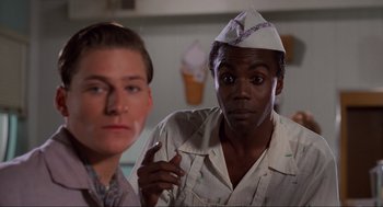 Movie still from “Back to the Future” (1985), directed by Robert Zemeckis – A man wearing a paper hat is standing next to another man; Close Up shot, Over the shoulder angle