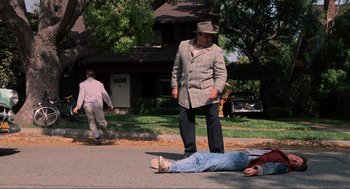 Movie still from “Back to the Future” (1985), directed by Robert Zemeckis – A man standing over another man laying on the ground; Wide shot, High angle