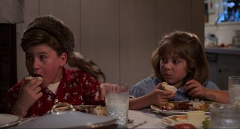 Movie still from “Back to the Future” (1985), directed by Robert Zemeckis – Two children sitting at a dinner table eating food; Medium shot, Over the shoulder angle