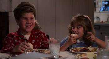 Movie still from “Back to the Future” (1985), directed by Robert Zemeckis – Two children eating pizza at a table with a glass of milk; Medium shot, Over the shoulder angle