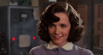 Movie still from “Back to the Future” (1985), directed by Robert Zemeckis – A young woman with brown curly hair wearing a purple sweater; Close Up shot, Over the shoulder angle