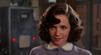 Movie still from “Back to the Future” (1985), directed by Robert Zemeckis – A young woman with brown curly hair wearing a purple sweater; Close Up shot, Over the shoulder angle