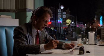 Movie still from “Back to the Future” (1985), directed by Robert Zemeckis – A man sitting at a table writing on a piece of paper; Medium shot, Low angle