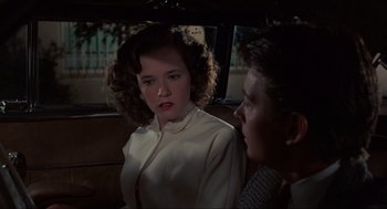 Movie still from “Back to the Future” (1985), directed by Robert Zemeckis – A woman in a white shirt and a man in a brown jacket in the back of a car; Medium shot, Over the shoulder angle