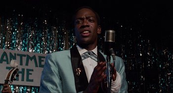 Movie still from “Back to the Future” (1985), directed by Robert Zemeckis – A man wearing a suit and tie holding a microphone; Close Up shot, Over the shoulder angle