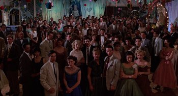 Movie still from “Back to the Future” (1985), directed by Robert Zemeckis – A large group of people standing in front of a stage; Wide shot, High angle