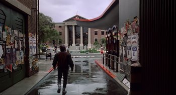 Movie still from “Back to the Future Part II” (1989), directed by Robert Zemeckis – A man walking down a street in the rain; Wide shot, Low angle