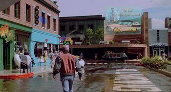 Movie still from “Back to the Future Part II” (1989), directed by Robert Zemeckis – A man walking down the street with a backpack; Extreme Wide shot, Over the shoulder angle