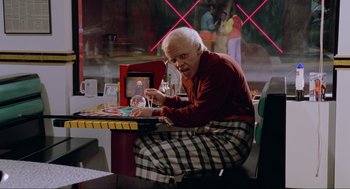 Movie still from “Back to the Future Part II” (1989), directed by Robert Zemeckis – An older man sitting at a table with a glass of wine; Medium shot, Low angle