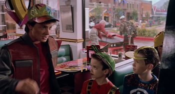 Movie still from “Back to the Future Part II” (1989), directed by Robert Zemeckis – A man and two boys wearing party hats in a restaurant; Medium shot, Over the shoulder angle