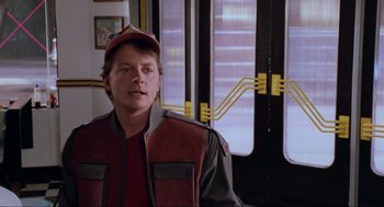 Movie still from “Back to the Future Part II” (1989), directed by Robert Zemeckis – A man wearing a red and black jacket and a red hat; Medium shot, Over the shoulder angle