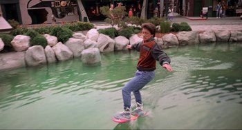 Movie still from “Back to the Future Part II” (1989), directed by Robert Zemeckis – A man riding a surfboard on top of a body of water; Wide shot, High angle