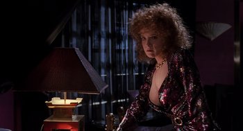 Movie still from “Back to the Future Part II” (1989), directed by Robert Zemeckis – A woman with curly red hair sitting in front of a lamp; Medium shot, Low angle