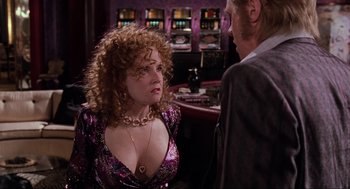 Movie still from “Back to the Future Part II” (1989), directed by Robert Zemeckis – A woman with curly red hair wearing a purple dress; Medium shot, Over the shoulder angle