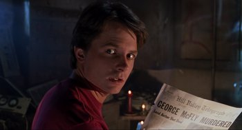 Movie still from “Back to the Future Part II” (1989), directed by Robert Zemeckis – A young man reading a newspaper in a dimly - lit room; Close Up shot, High angle