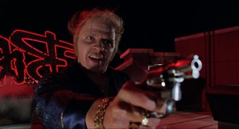 Movie still from “Back to the Future Part II” (1989), directed by Robert Zemeckis – An older woman holding a gun in a dark room; Medium shot, Low angle