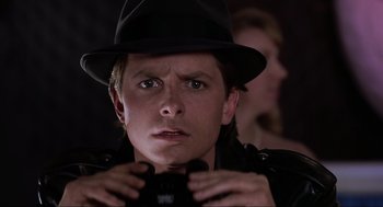 Movie still from “Back to the Future Part II” (1989), directed by Robert Zemeckis – A man in a hat is holding a camera; Close Up shot, Over the shoulder angle