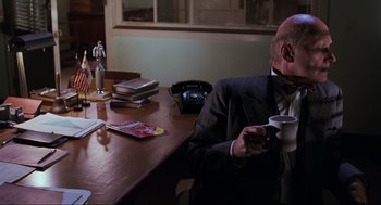 Movie still from “Back to the Future Part II” (1989), directed by Robert Zemeckis – An older man sitting at a table drinking coffee; Medium shot, Low angle