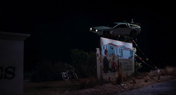 Movie still from “Back to the Future Part II” (1989), directed by Robert Zemeckis – A car flying over a billboard in the dark; Extreme Wide shot, Low angle