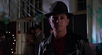 Movie still from “Back to the Future Part II” (1989), directed by Robert Zemeckis – A man wearing a black hat and a leather jacket; Close Up shot, Over the shoulder angle