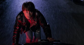 Movie still from “Back to the Future Part II” (1989), directed by Robert Zemeckis – A man in a red jacket is leaning over a table; Medium shot, Overhead angle