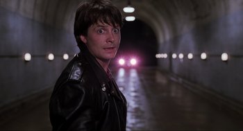 Movie still from “Back to the Future Part II” (1989), directed by Robert Zemeckis – A man standing in a tunnel with a car in the background; Close Up shot, Over the shoulder angle