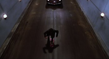 Movie still from “Back to the Future Part II” (1989), directed by Robert Zemeckis – A man riding a skateboard down the side of a road; Wide shot, Overhead angle