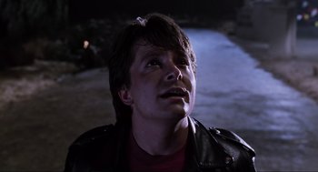 Movie still from “Back to the Future Part II” (1989), directed by Robert Zemeckis – A young man wearing a leather jacket looking up at the sky; Close Up shot, Low angle