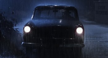 Movie still from “Back to the Future Part II” (1989), directed by Robert Zemeckis – A black car is driving in the rain at night; Wide shot, Low angle