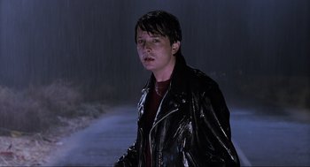 Movie still from “Back to the Future Part II” (1989), directed by Robert Zemeckis – A man in a leather jacket standing in the rain; Close Up shot, Over the shoulder angle