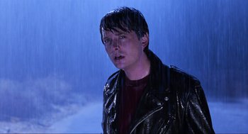 Movie still from “Back to the Future Part II” (1989), directed by Robert Zemeckis – A man in a leather jacket standing in the pouring rain; Close Up shot, Over the shoulder angle