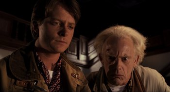 Movie still from “Back to the Future Part III” (1990), directed by Robert Zemeckis – A man standing next to another man in a dark room; Close Up shot, Low angle