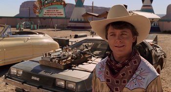 Movie still from “Back to the Future Part III” (1990), directed by Robert Zemeckis – A man wearing a cowboy hat standing in front of a car; Medium shot, Over the shoulder angle