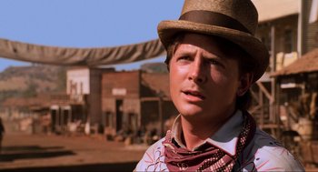 Movie still from “Back to the Future Part III” (1990), directed by Robert Zemeckis – A young man in a cowboy hat is standing in front of an old western town; Close Up shot, Low angle