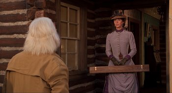 Movie still from “Back to the Future Part III” (1990), directed by Robert Zemeckis – A woman dressed in period clothing and holding a wooden box; Medium shot, Over the shoulder angle