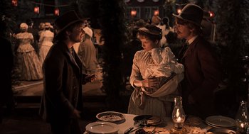 Movie still from “Back to the Future Part III” (1990), directed by Robert Zemeckis – A group of people standing around a table with food on top of it; Medium shot, Over the shoulder angle