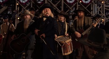 Movie still from “Back to the Future Part III” (1990), directed by Robert Zemeckis – A group of men in hats are playing musical instruments; Medium shot, Low angle