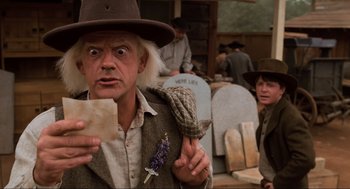 Movie still from “Back to the Future Part III” (1990), directed by Robert Zemeckis – A man in a hat holding a piece of paper in his hand; Medium shot, Low angle