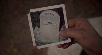 Movie still from “Back to the Future Part III” (1990), directed by Robert Zemeckis – A person holding up a picture of a tombstone; Extreme Close Up shot, High angle