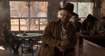 Movie still from “Back to the Future Part III” (1990), directed by Robert Zemeckis – A man in a brown jacket and a brown cowboy hat; Medium shot, Over the shoulder angle
